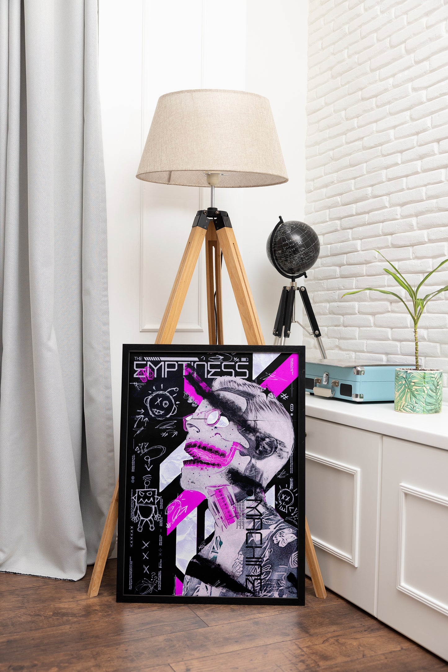 The Emptiness Machine poster framed in black, showcasing a spiritual cyborg, vibrant pink background, and intricate hand-drawn grunge details, styled in an adventure-themed room with a globe.