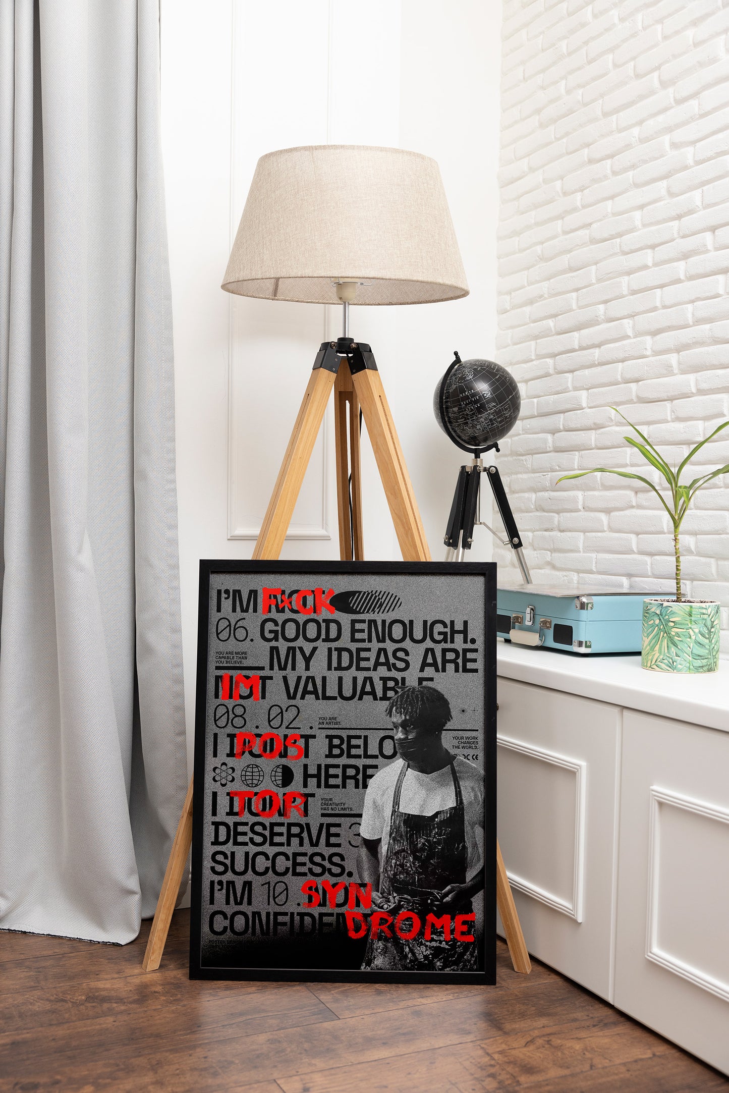 Impostor Syndrome poster framed in black, showcasing meticulous typography, expressive red brushstrokes, and an African artist figure, styled in an adventure-themed room with a globe.